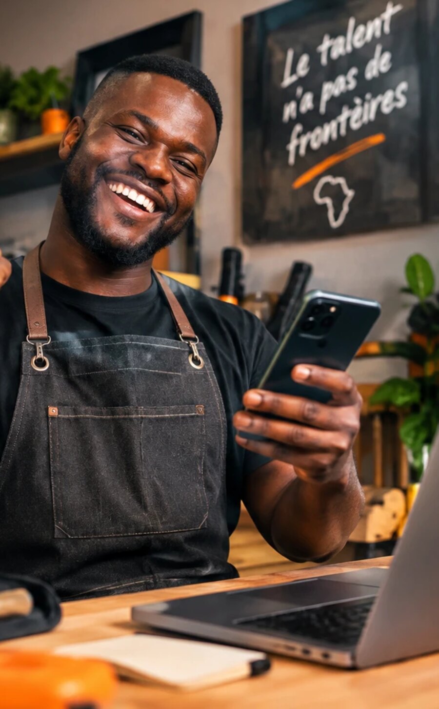 Un prestataire 2KRIKA souriant dans son atelier, téléphone à la main